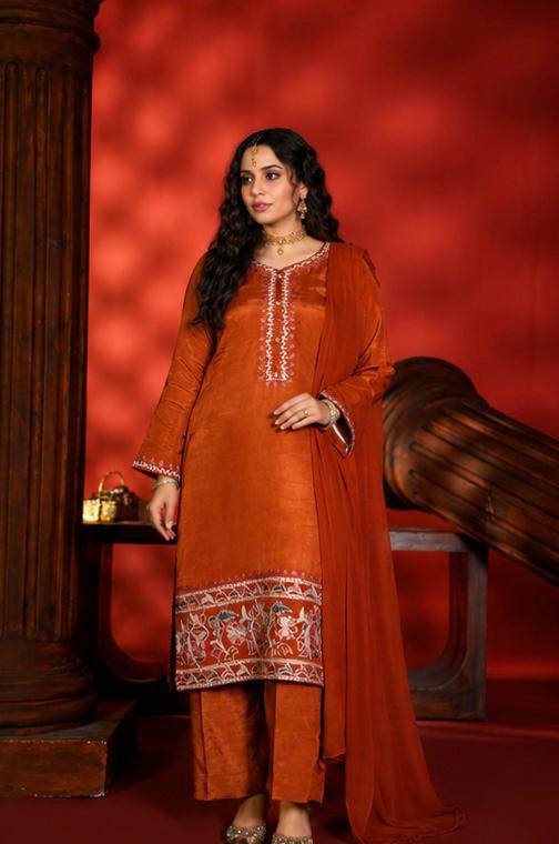 Woman in an orange traditional outfit with intricate patterns against a red background