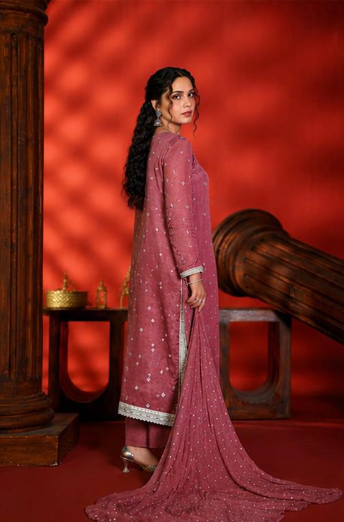 Woman in a pink traditional outfit standing against a red background